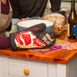Person holding a pot with the Meat Mitt oven mitt. Photo © Blue Q