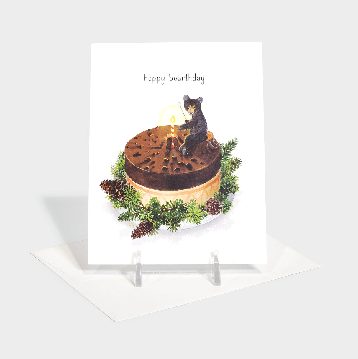 Greeting card with illustration of a bear on a cake. The bear is using the birthday candle to roast marshmallows.