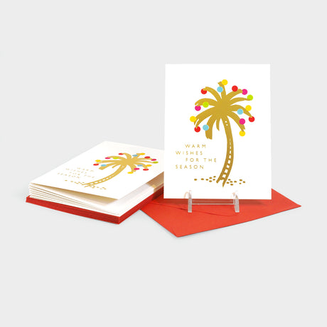 Greeting cards with a gold foil-stamped palm tree with colorful ornaments decorating the leaves.