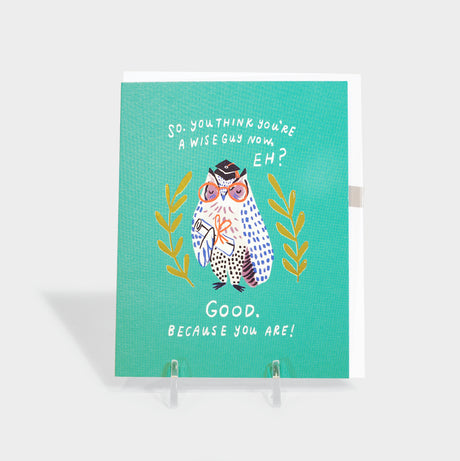 Greeting card with owl in graduation hat holding a diploma.