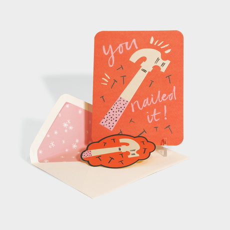 Greeting card with die-cut sealing sticker. Card features an illustration of a hammer and nails.